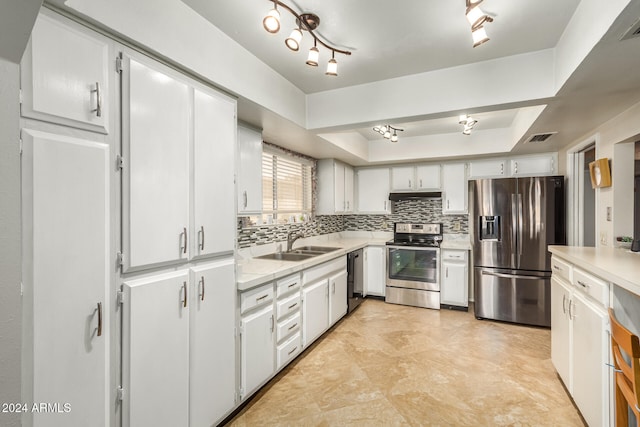 kitchen featuring stainless steel appliances, white cabinets, sink, a raised ceiling, and backsplash