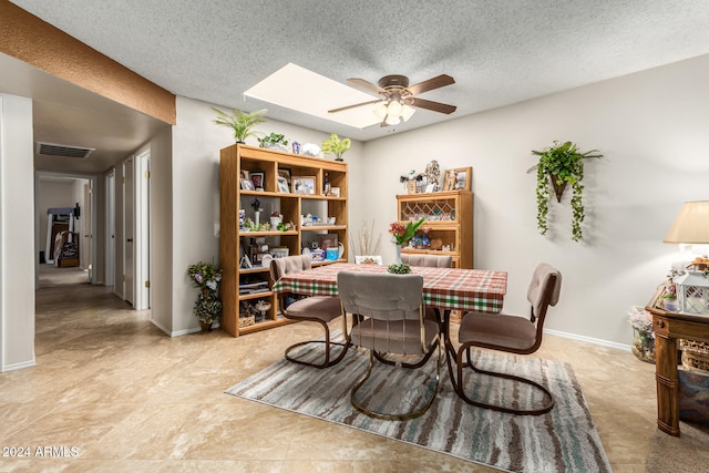 dining room featuring a skylight, a textured ceiling, and ceiling fan