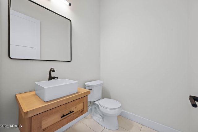 half bathroom with tile patterned flooring, toilet, vanity, and baseboards