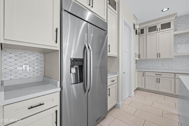 kitchen with open shelves, tasteful backsplash, glass insert cabinets, and stainless steel fridge