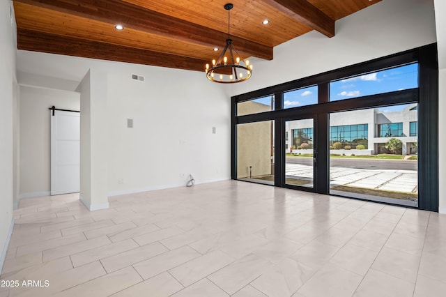 unfurnished room with visible vents, beam ceiling, a barn door, wooden ceiling, and a chandelier