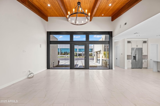 interior space featuring visible vents, a high ceiling, an inviting chandelier, baseboards, and wood ceiling