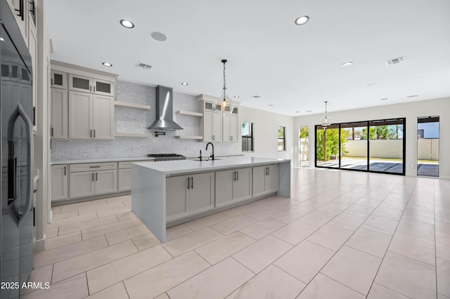 kitchen featuring visible vents, a sink, open shelves, open floor plan, and wall chimney exhaust hood