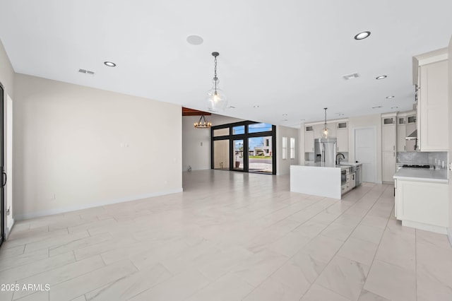 unfurnished living room with visible vents, recessed lighting, an inviting chandelier, and a sink