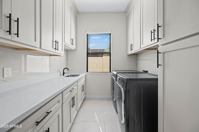 clothes washing area with a sink, baseboards, cabinet space, and independent washer and dryer