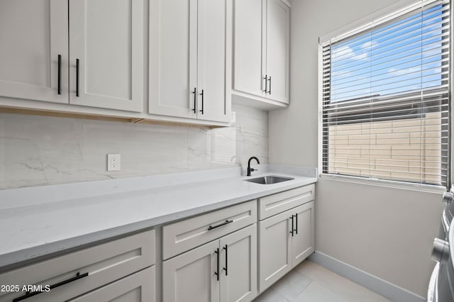 kitchen featuring tasteful backsplash, baseboards, and a sink