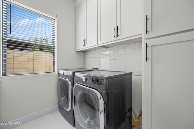 washroom featuring washing machine and clothes dryer, cabinet space, and baseboards