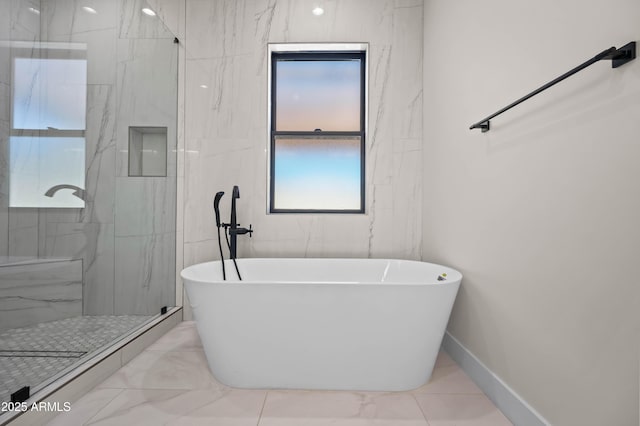 bathroom with a marble finish shower, marble finish floor, a freestanding bath, and baseboards