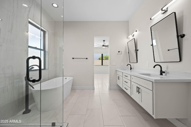 full bath with double vanity, a freestanding tub, baseboards, and a sink