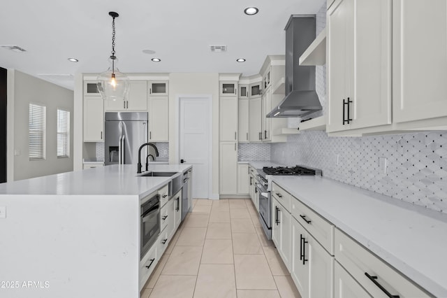 kitchen with visible vents, an island with sink, stainless steel appliances, wall chimney exhaust hood, and a sink