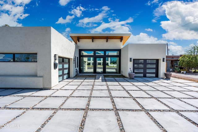 view of front facade with a garage, driveway, and stucco siding