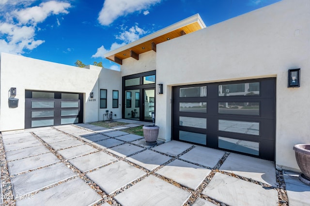 view of exterior entry featuring stucco siding, driveway, and a garage