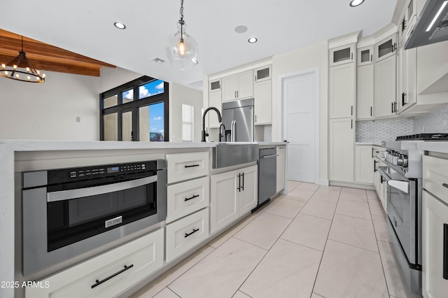 kitchen with hanging light fixtures, decorative backsplash, stainless steel appliances, and light countertops