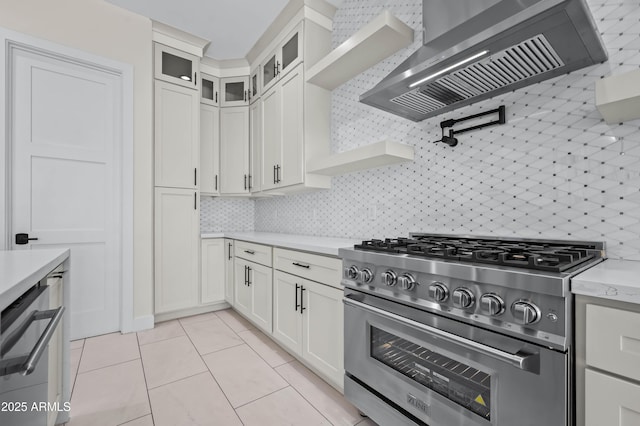 kitchen featuring light countertops, wall chimney exhaust hood, tasteful backsplash, and appliances with stainless steel finishes