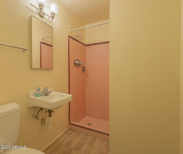 bathroom featuring a tile shower, toilet, and sink