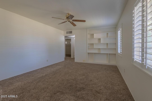 interior space with carpet flooring, a wealth of natural light, built in features, and ceiling fan