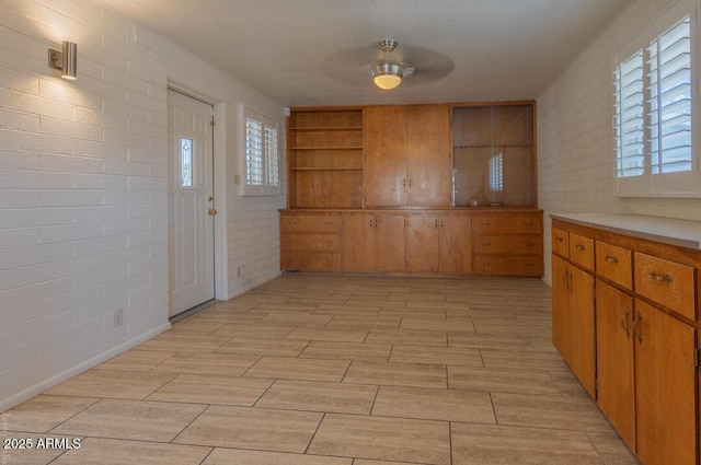 kitchen featuring ceiling fan, plenty of natural light, and brick wall