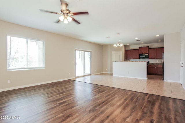 24479 W Mobile Ln, Buckeye, AZ 85326 - unfurnished living room featuring light wood finished floors, baseboards, recessed lighting, and ceiling fan with notable chandelier