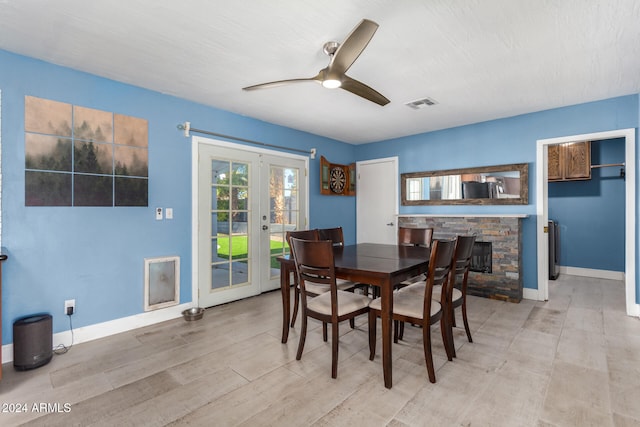 dining room with a fireplace, french doors, light hardwood / wood-style floors, and ceiling fan