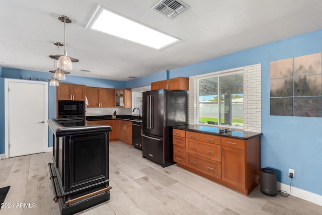 kitchen featuring light wood-type flooring, tasteful backsplash, black appliances, pendant lighting, and a kitchen island