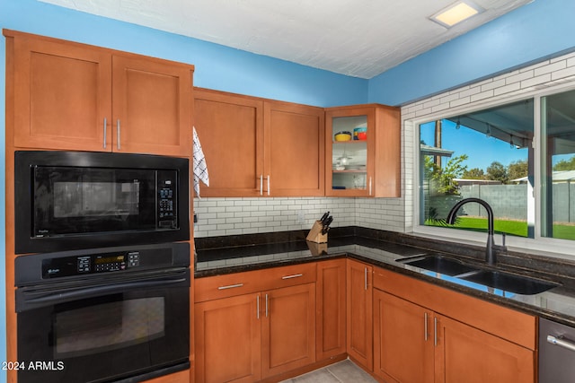 kitchen featuring black appliances, decorative backsplash, dark stone countertops, and sink