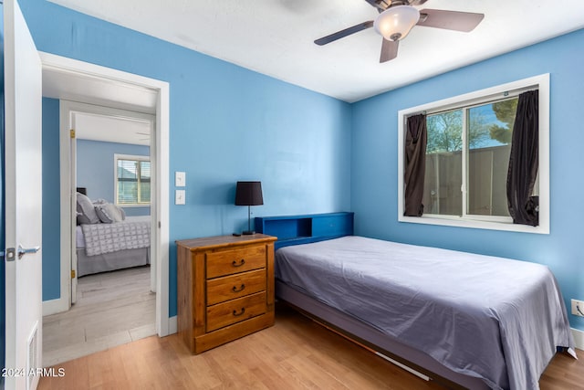 bedroom with multiple windows, ceiling fan, and light wood-type flooring