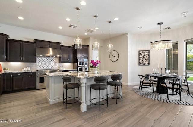 2821 E Cashman Dr, Phoenix, AZ 85050 - kitchen with stainless steel appliances, under cabinet range hood, light wood finished floors, baseboards, and decorative backsplash