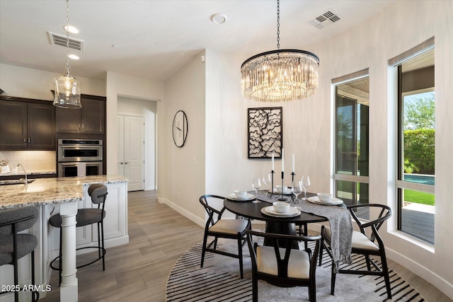 2821 E Cashman Dr, Phoenix, AZ 85050 - dining space featuring baseboards, light wood finished floors, and a chandelier