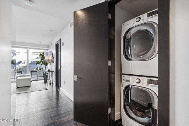 laundry room featuring dark hardwood / wood-style floors and stacked washer and clothes dryer