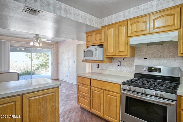 kitchen featuring light wood-type flooring, stainless steel gas range oven, and ceiling fan