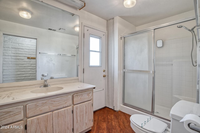 bathroom featuring hardwood / wood-style floors, vanity, a shower with shower door, and toilet