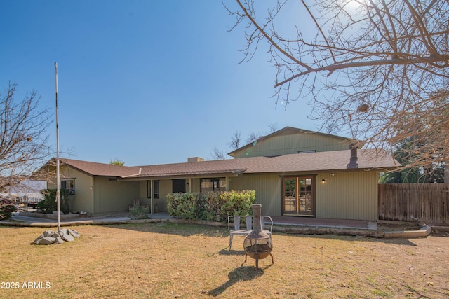 back of property with a lawn and an outdoor fire pit