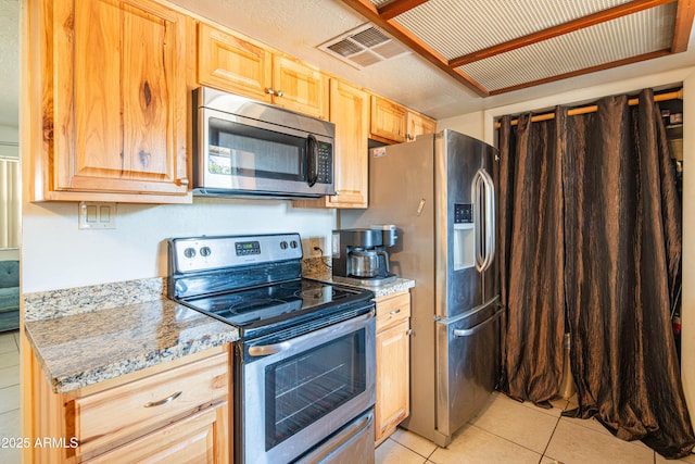 kitchen featuring appliances with stainless steel finishes, light stone countertops, light brown cabinets, and light tile patterned floors