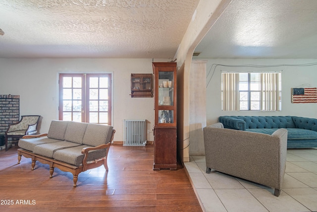 living room with hardwood / wood-style floors, radiator heating unit, a textured ceiling, and french doors