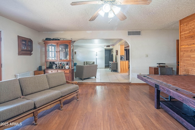 living room with radiator, a textured ceiling, light hardwood / wood-style floors, and ceiling fan