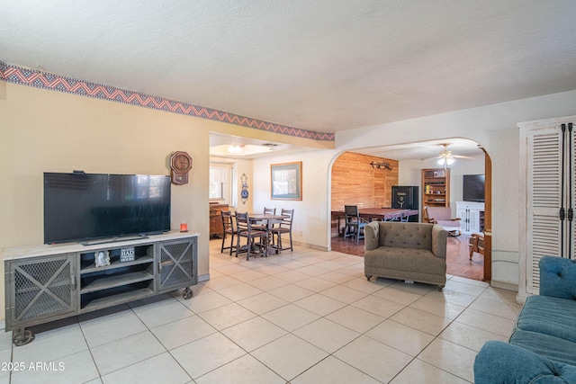 tiled living room featuring ceiling fan and a textured ceiling