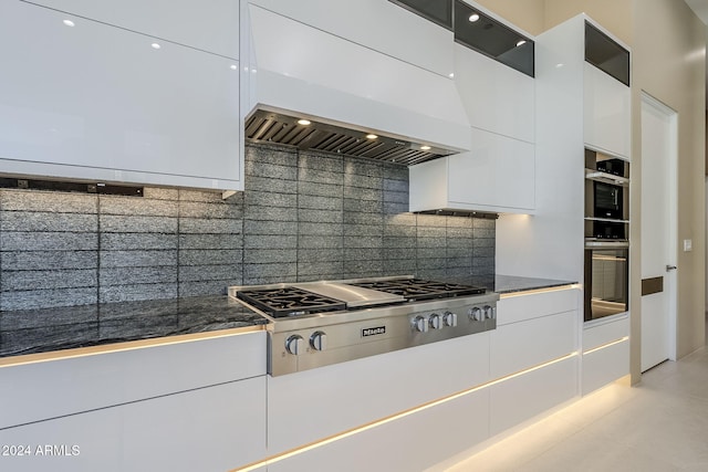 kitchen with decorative backsplash, white cabinetry, premium range hood, and stainless steel appliances