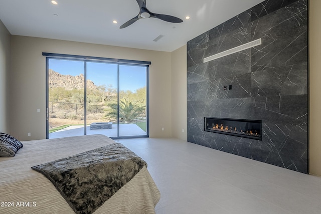 bedroom with access to exterior, ceiling fan, tile walls, and a tiled fireplace