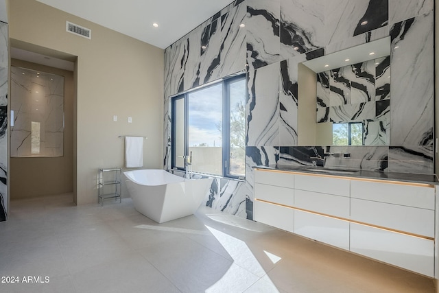 bathroom featuring tile patterned floors, vanity, a tub, and tile walls