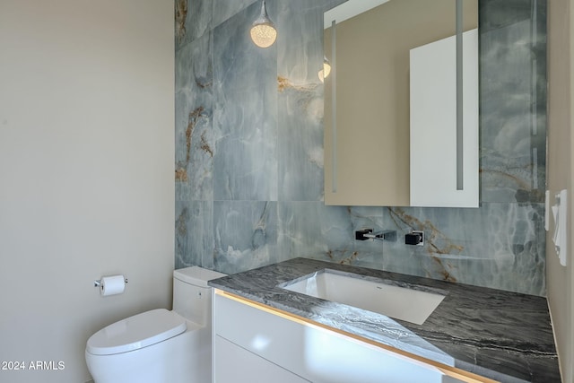 bathroom featuring vanity, toilet, and backsplash