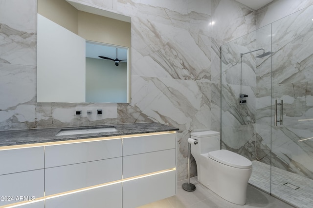 bathroom featuring vanity, a shower with door, ceiling fan, tile walls, and toilet