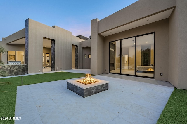 back house at dusk featuring a patio area and an outdoor fire pit