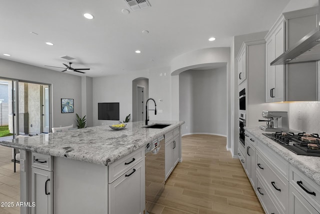 kitchen featuring white cabinetry, sink, stainless steel dishwasher, black gas stovetop, and a center island with sink