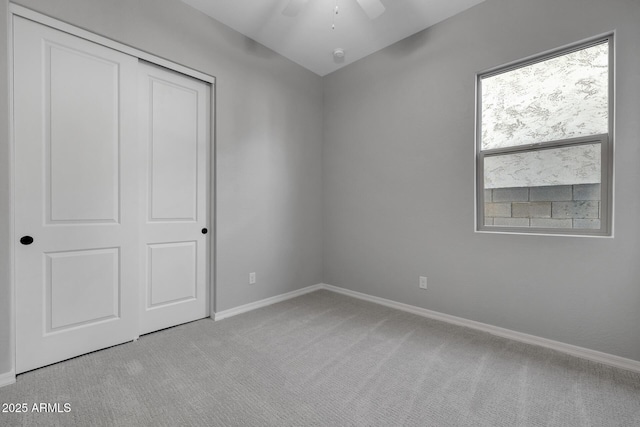 unfurnished bedroom with light carpet, ceiling fan, and a closet