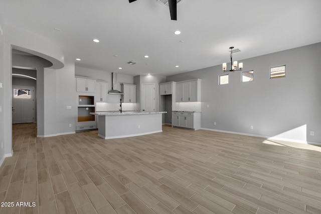 unfurnished living room featuring ceiling fan with notable chandelier and sink