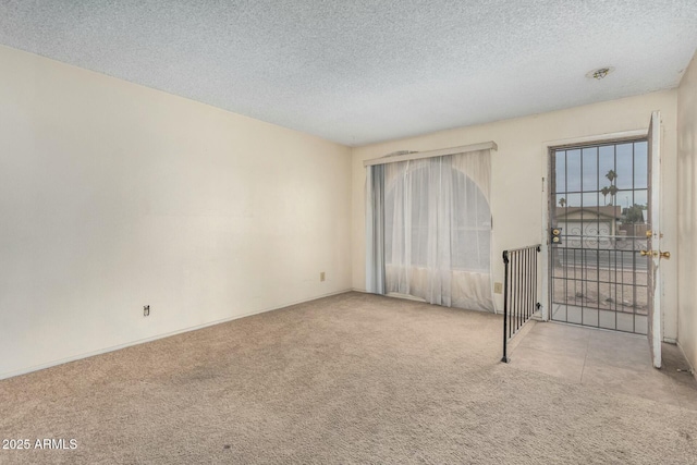 unfurnished room with light colored carpet and a textured ceiling