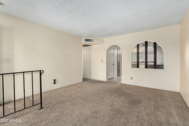 empty room featuring a textured ceiling and carpet flooring