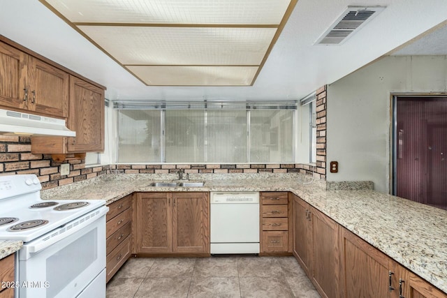 kitchen with light tile patterned flooring, sink, light stone counters, and white appliances