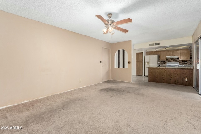 unfurnished living room with ceiling fan and a textured ceiling