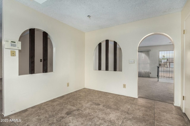 carpeted empty room featuring a textured ceiling